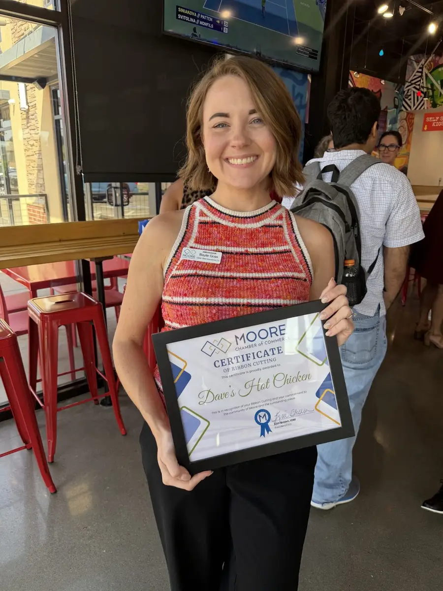 Holding the Moore Chamber ribbon-cutting certificate at Dave's Hot Chicken