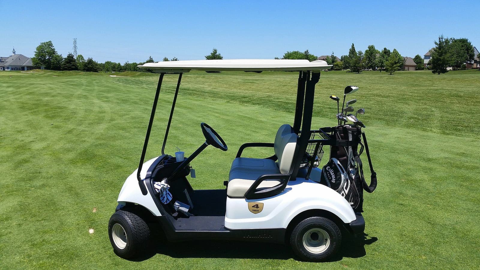 A golf cart parked on a fairway with a bag of clubs